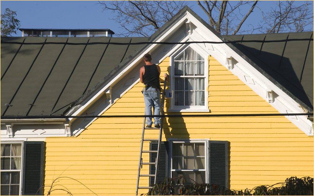 Painter repainting the gable end of a house exterior
